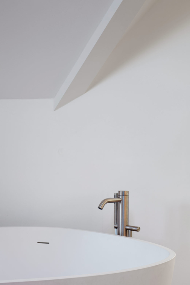 Interiorfotografie Lioba Schneider: Schlichte elegante Armatur über einer freistehenden weissen Badewanne.