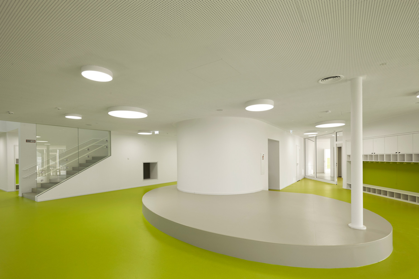 Architekturfotografie Lioba Schneider: Neubau des Kita der Bayer AG in Leverkusen in Holzbauweise. Der sehr grüne Bodenbelag kontrastiert sehr zu den weisen Wänden.