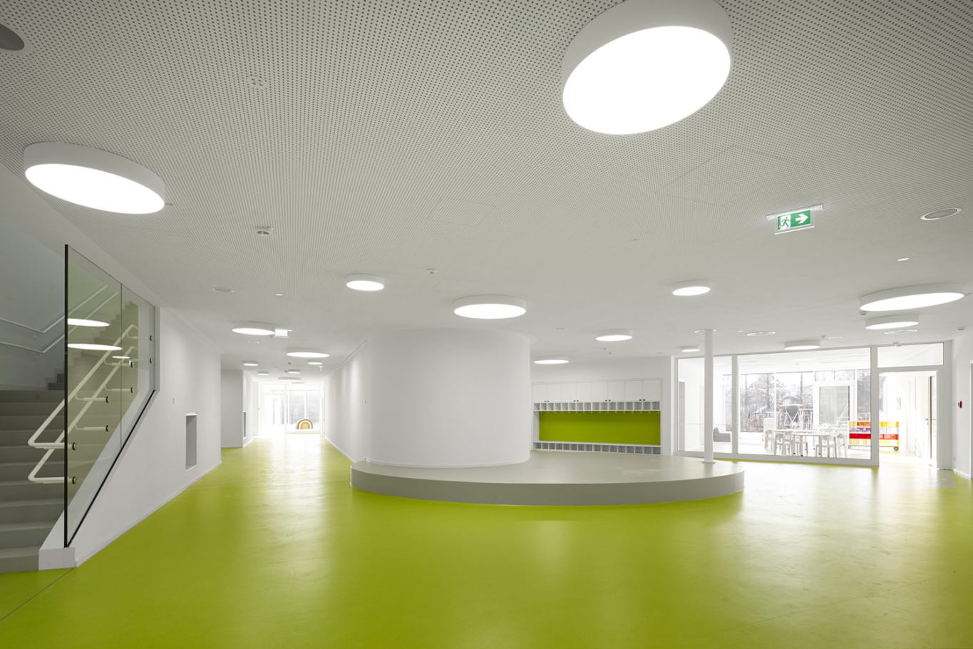 Architekturfotografie Lioba Schneider: Neubau des Kita der Bayer AG in Leverkusen in Holzbauweise. Der sehr grüne Bodenbelag kontrastiert sehr zu den weisen Wänden.