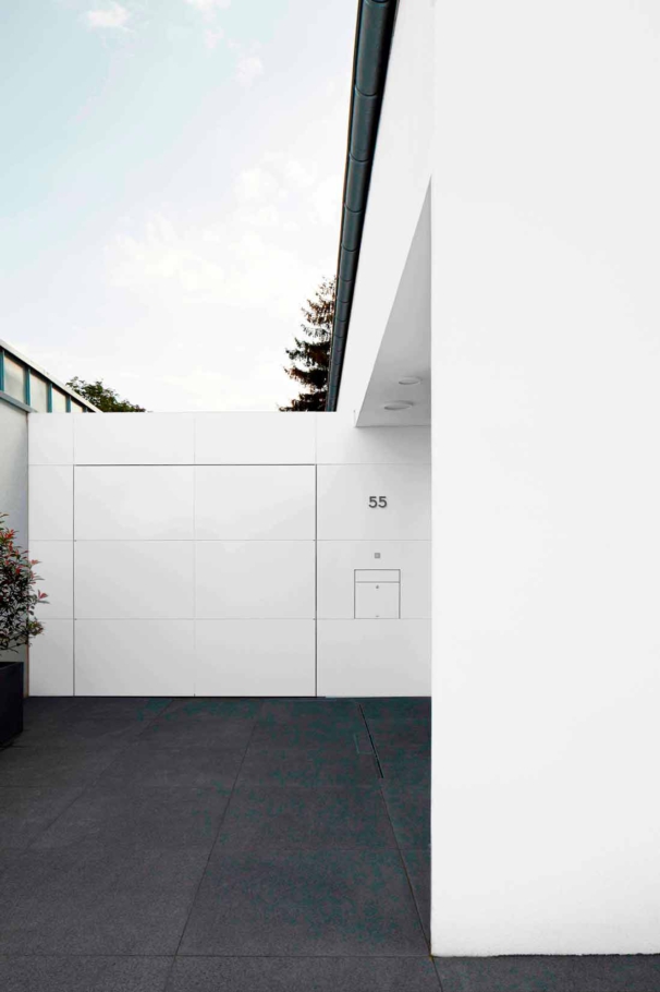 Architekturfotografie Lioba Schneider: Weisses Einfamilienhaus in Troisdorf. Die in weiss gehaltene Garage schliesst sich bündig ans Haus an, vom weissen Garagentor sieht man nur eine Fuge.