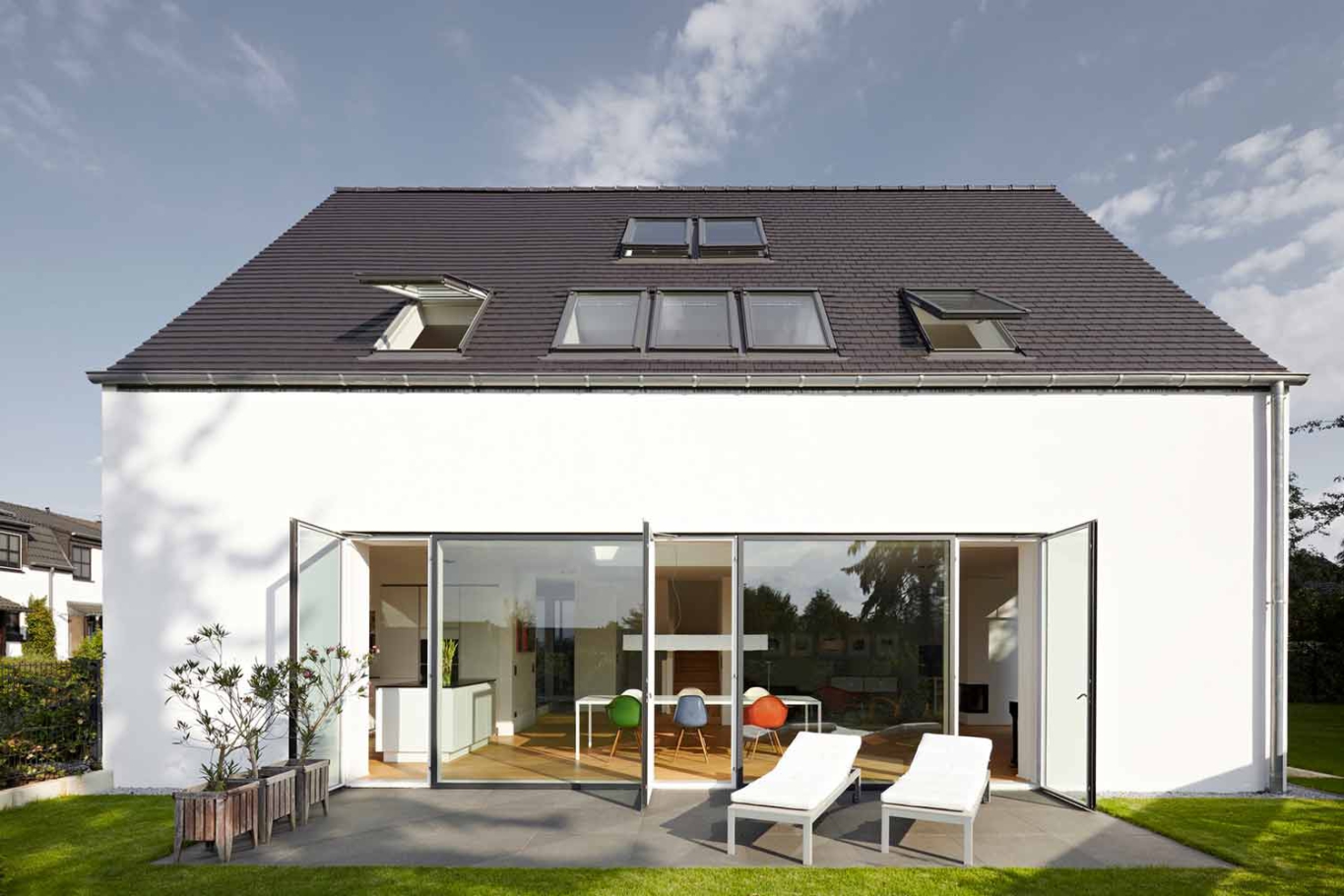 Architekturfotografie Lioba Schneider: Weisses Einfamilienhaus in Troisdorf. Große Flügeltüren aus Glas öffnen nach aussen auf die sonnendurchflutete Terrasse.