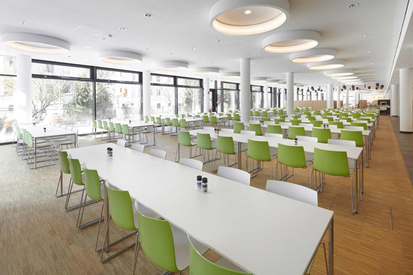 Architekturfotografie Lioba Schneider: Neubau des Vodafone-Campus in Düsseldorf. Große Kantine mit unterschiedlicher Bestuhlung und Beleuchtung, wodurch verschiedene Zonen entstehen.