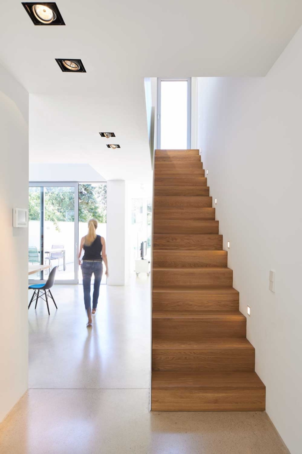 Architekturfotografie Lioba Schneider: Helles Interior eines Doppelhauses in Bonn. Die Treppe aus Holz kontrastiert zu den weissen Wänden und Böden. Durchblick bis in den Garten.