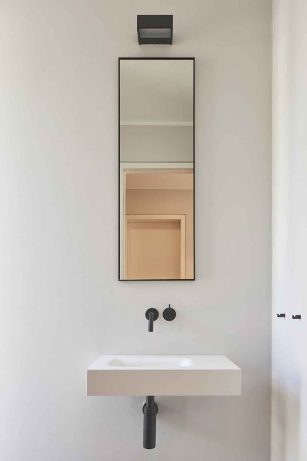 Architekturfotografie Lioba Schneider: Helles Interior eines Doppelhauses in Bonn. Modern reduzierte schwarze Badarmatur über schlichtem Waschbecken in der Gästetoilette.