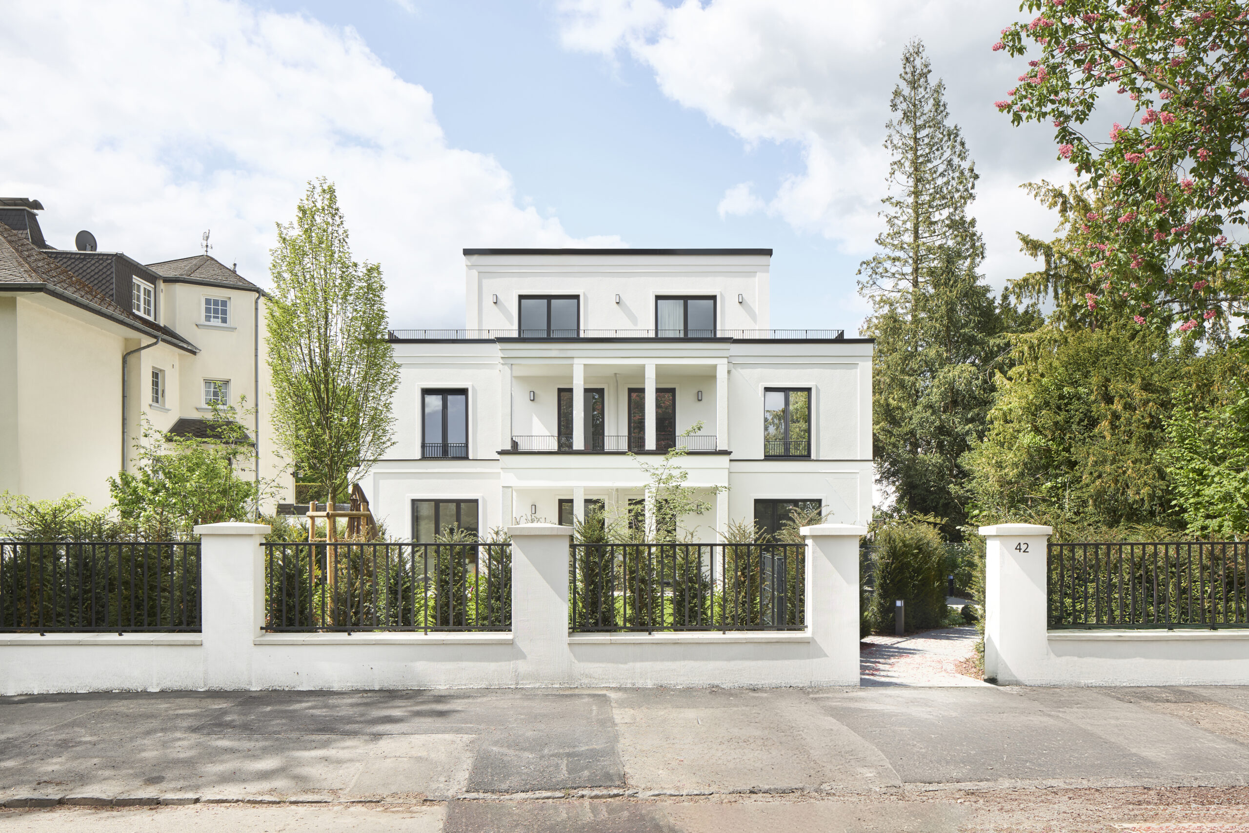 Architekturfotografie eines Mehrfamilienhauses in Bonn. Eine Aussenaufnahme zeigt ein dreistöckiges weisses elegantes MFH mit zurückspringender Attika.