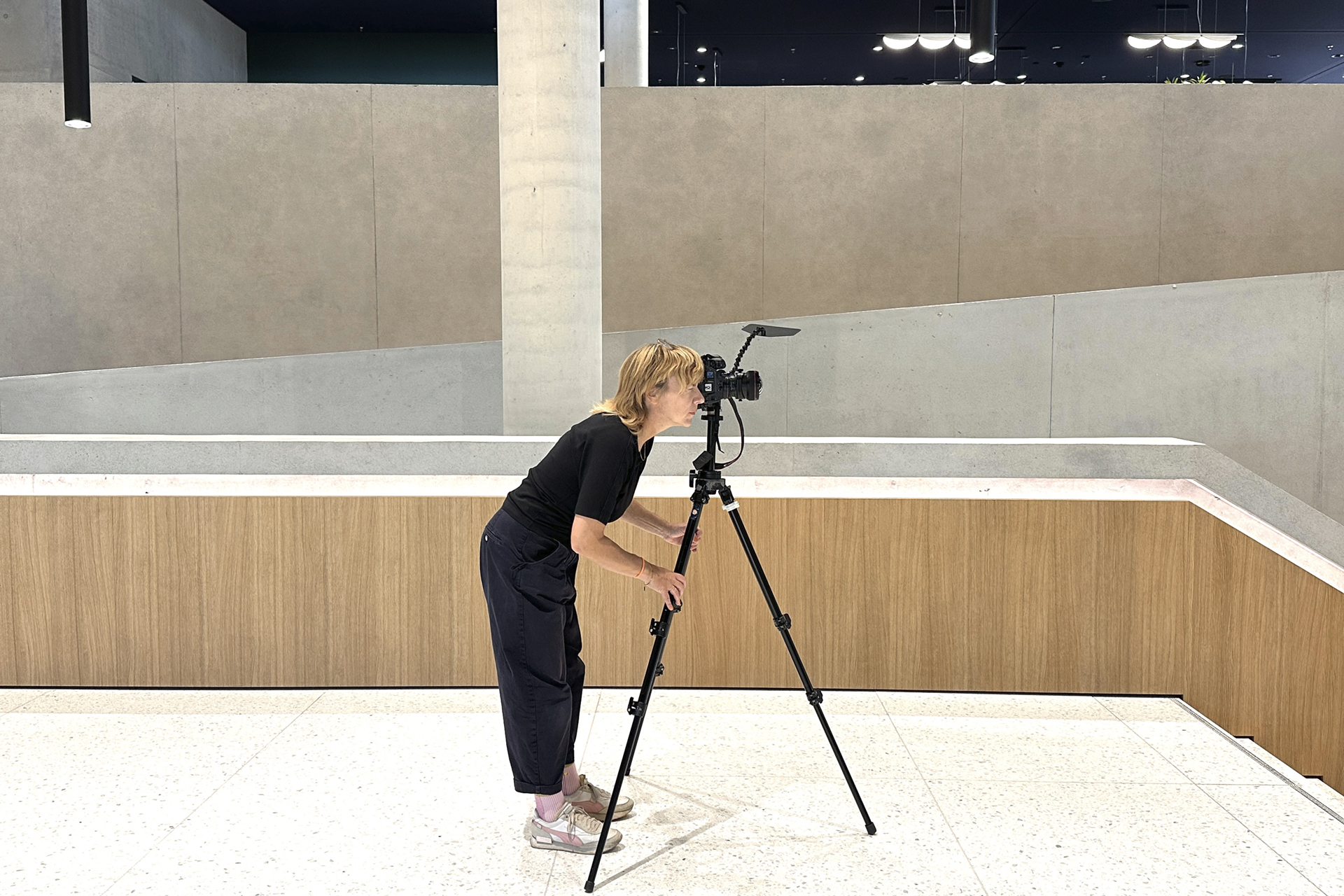 Die Architekturfotografin Lioba Schneider fotografiert mit einem Stativ ein modernes Gebäude innen.